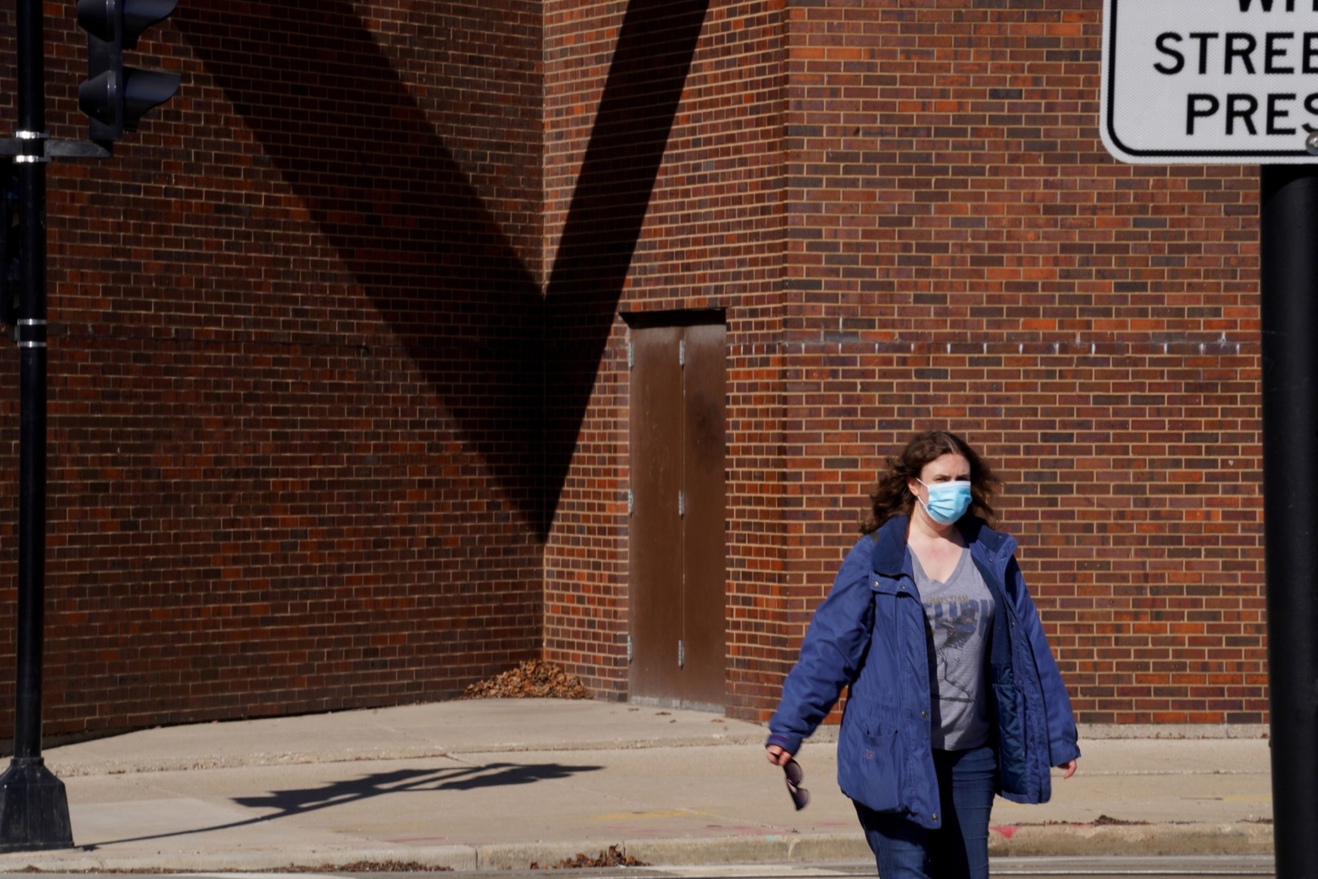A pedestrian wearing a protective mask walks along a street in Milwaukee, Wisconsin, U.S., on Thursday, April 2, 2020. A federal judge refused to postpone Wisconsin's presidential primary on Tuesday, but extended the deadline for absentee voting by a week. Photographer: Thomas Werner/Bloomberg