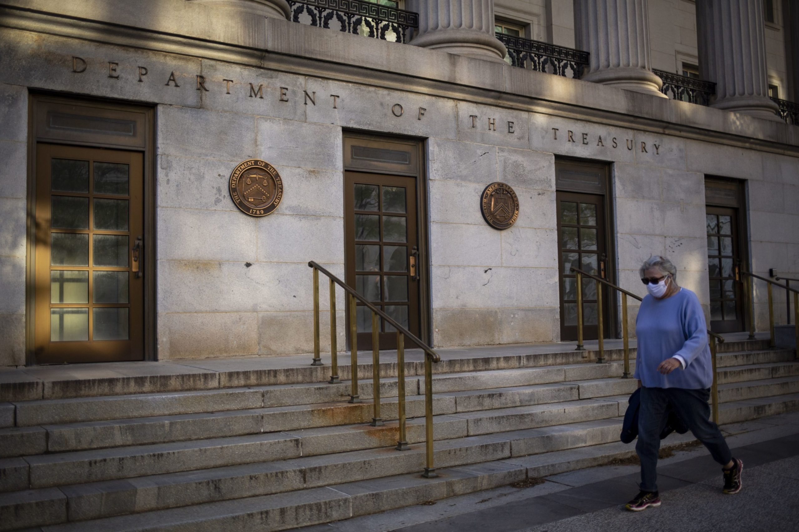 A pedestrian wearing a protective mask passes the U.S. Treasury building in Washington, D.C., U.S., on Thursday, April 16, 2020. Photographer: Al Drago/Bloomberg