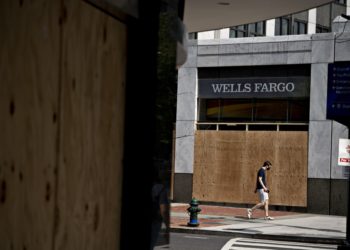 A pedestrian wearing a protective mask walks past a boarded up  Wells Fargo & Co. bank branch in Washington, D.C., U.S., on Thursday, June 4, 2020. Photographer: Andrew Harrer/Bloomberg