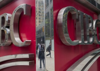 Pedestrians are reflected in signage on the exterior of the Canadian Imperial Bank of Commerce (CIBC) headquarters building in Toronto, Ontario, Canada, on Friday, May 19, 2017. Image via Bloomberg.